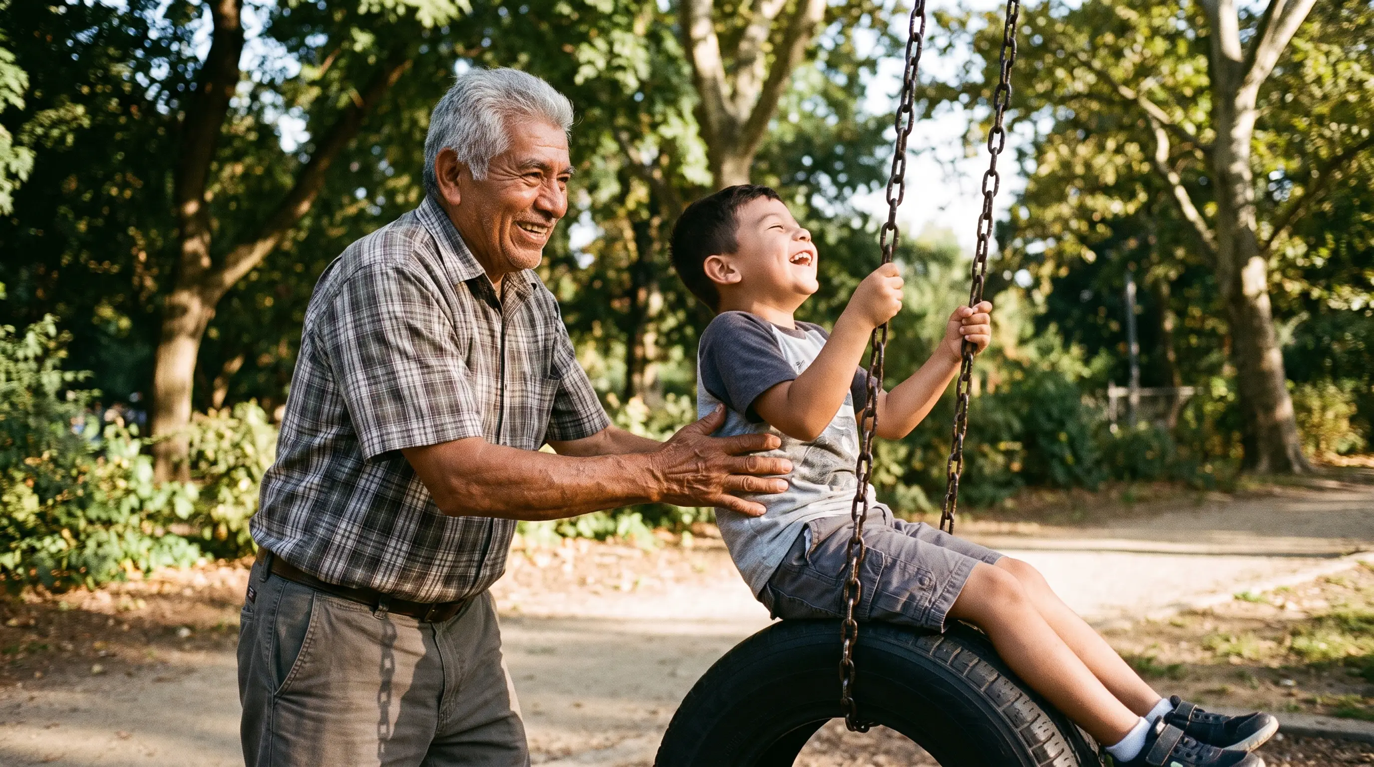 A grandfather in his 70s pushes his grandson on a tire swing